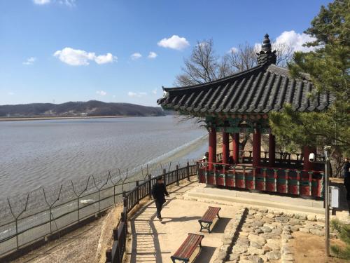 a person walking in front of a pavilion by the water at The Guesthouse DMZ Stay in Paju