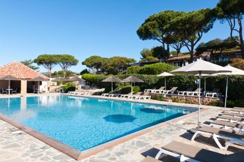 a large swimming pool with lounge chairs and umbrellas at Résidence Marina Di Santa Giulia in Porto-Vecchio