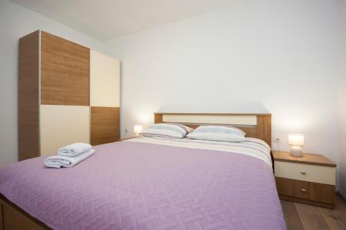 a bedroom with a purple bed with two towels on it at Apartment Marsela in Šibenik