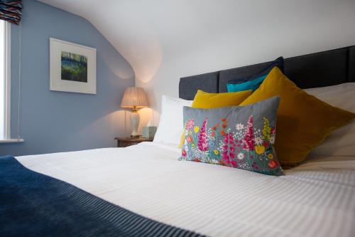 1 dormitorio con cama blanca y almohadas coloridas en Moortown Lodge B&B en Ringwood