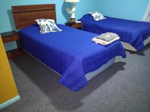 two beds with blue sheets in a room at Hostal El Toque de Pilar in Punta Arenas