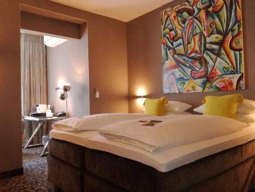 a bedroom with a large bed with a painting on the wall at Top Hotel Krämer in Koblenz