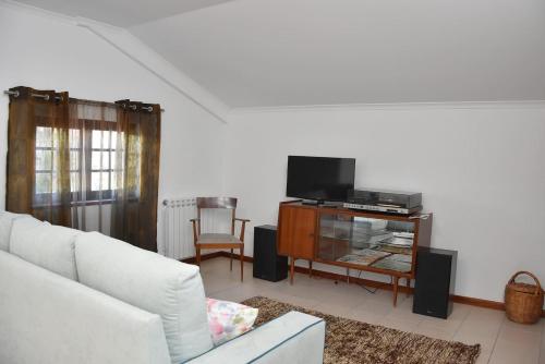 a living room with a white couch and a tv at Casa Mouramortina in Vila Nova de Poiares