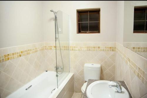a bathroom with a tub and a toilet and a sink at Ocean View Villas Unit A11 in Port Edward