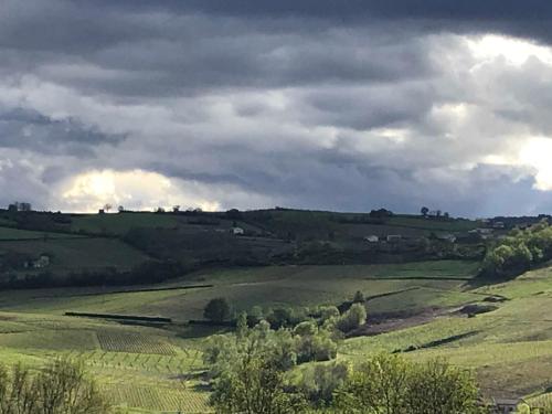 a view of a green field under a cloudy sky at Chambres d'hôtes Vers la Croix in Leynes