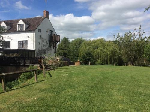 una antigua casa blanca con un gran patio en The Old Mill, en Shipston on Stour