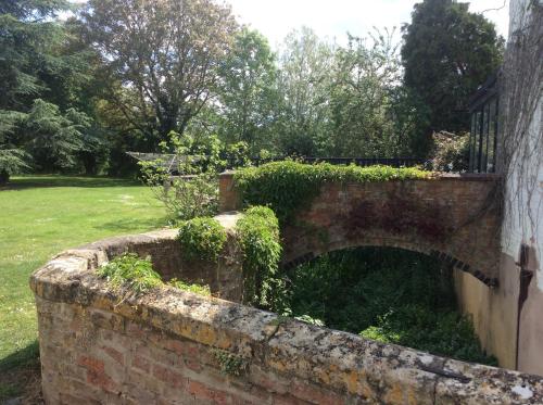 uma velha parede de tijolos com hera a crescer nela em The Old Mill em Shipston on Stour