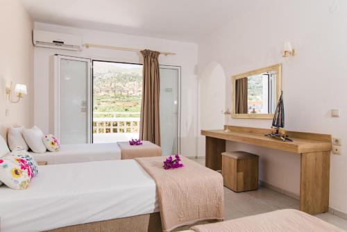 a hotel room with two beds and a window at Emerald Hotel in Malia