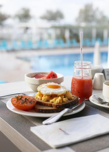 een ontbijtbord met eieren en tomaten en een drankje bij Universal Hotel Castell Royal in Canyamel