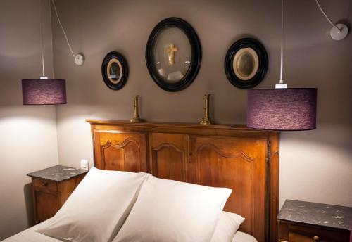 a bedroom with a wooden headboard and three mirrors at Hotel Auberge des Remparts in Laval