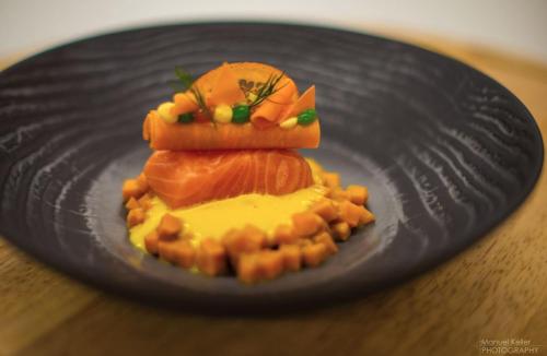 a black plate with food on a wooden table at Aktiv- & Wellnesshotel Bergfried in Tux