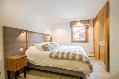 Schlafzimmer mit einem großen Bett mit einem Kopfteil aus Holz in der Unterkunft PORTES DU PLENEY 101 in Morzine