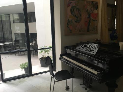 a piano in a room with a chair and a balcony at Art Hotel Athens in Athens