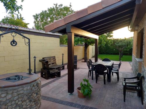 a patio with a table and chairs and a stone wall at La Casita Del Abuelo in Villalmanzo