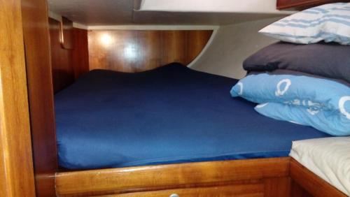 a bed on a boat with blue sheets and pillows at Velero MissTick,Gibsea 47'2 in Puerto Calero