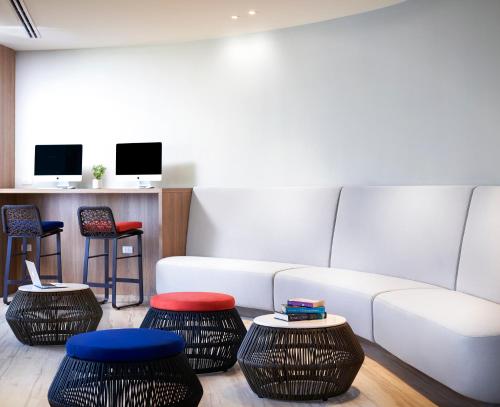a living room with a white couch and two stools at OZO Phuket in Kata Beach