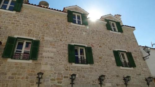 a building with green shuttered windows on it at Centar Vodice Apartmani in Vodice
