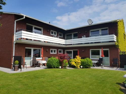 un edificio de ladrillo rojo con césped delante en Auszeit Norddeich I 5 Minuten zu Fuß zum Meer, en Norddeich