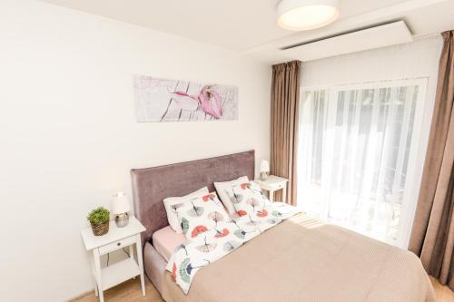 um quarto com uma cama com almofadas e uma janela em Apartments Family - Vėsa em Palanga