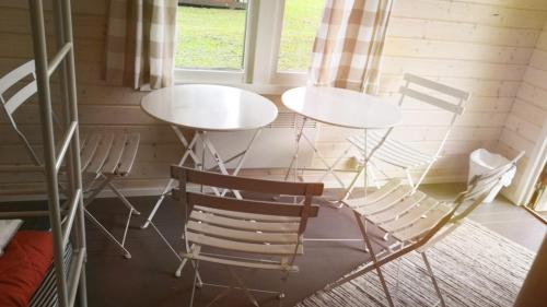 a room with two white tables and chairs at Koljonvirta Camping in Iisalmi