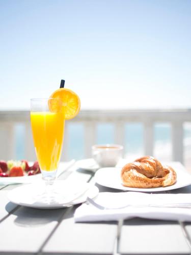 a glass of orange juice sitting on a table with food at Hotel Chiqui in Santander