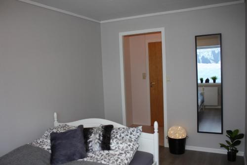 a bedroom with a white bed and a mirror at Studioleilighet i Haukedalen in Holsen