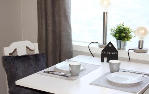 Una mesa blanca con dos platos y tazas. en Studioleilighet i Haukedalen, en Holsen