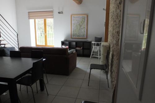 ein Wohnzimmer mit einem Sofa, einem Tisch und Stühlen in der Unterkunft Gîte Séchoir du Nan in Cognin-les-Gorges