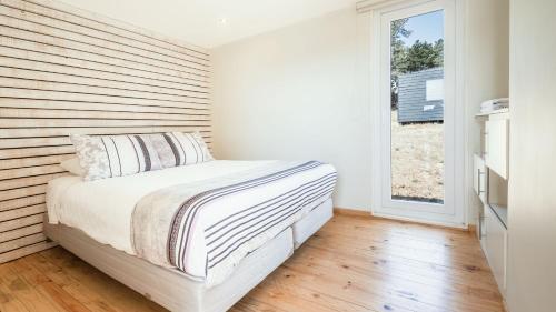 sypialnia z łóżkiem z drewnianą ścianą w obiekcie Curi Lodge Pichilemu w mieście Pichilemu