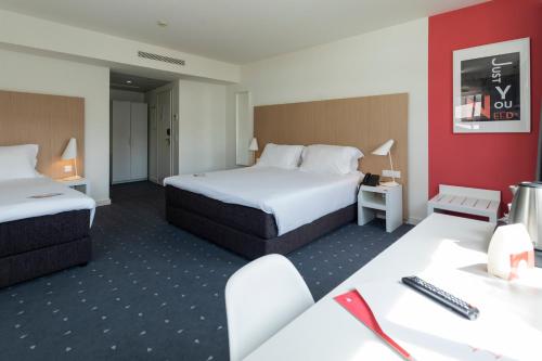a hotel room with two beds and a desk at Stay Hotel Coimbra Centro in Coimbra