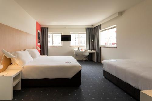 a hotel room with two beds and a desk at Stay Hotel Coimbra Centro in Coimbra