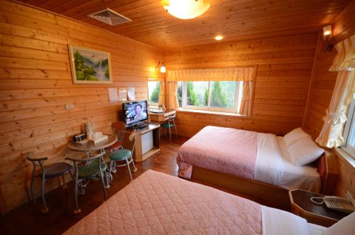 a room with two beds and a television in a cabin at Sea of Clouds Vacation Villa in Renai