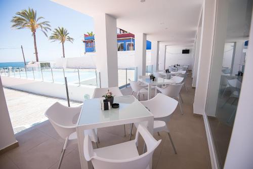 a restaurant with white tables and white chairs and the ocean at Hotel Soul de Javea in Jávea