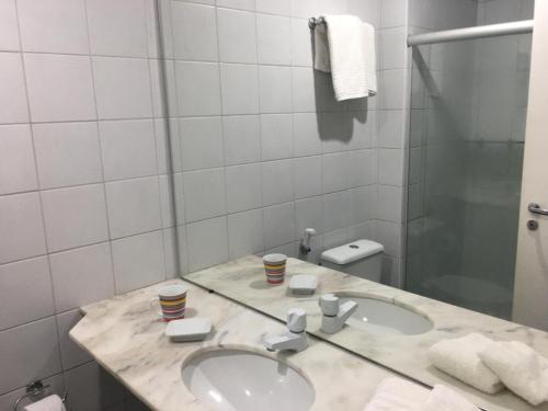 a white bathroom with a sink and a toilet at Praia do Forte - Frente ao Mar in Praia do Forte
