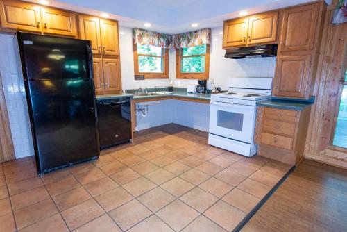 a kitchen with wooden cabinets and a black refrigerator at Carter Caves State Resort Park in Olive Hill