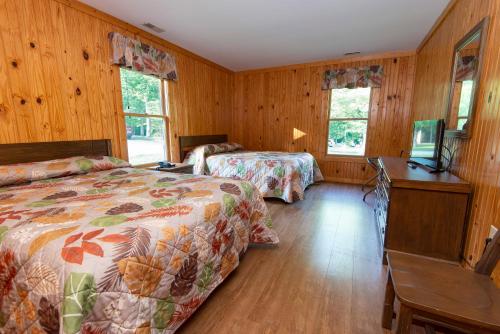 a bedroom with two beds and a desk and two windows at Carter Caves State Resort Park in Olive Hill