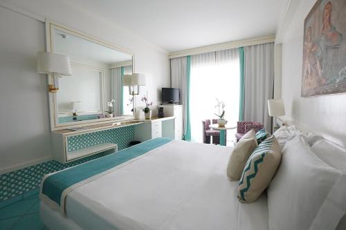 a bedroom with a large bed and a large mirror at Grand Hotel Terme in Margherita di Savoia