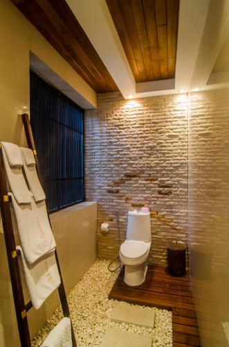 a bathroom with a toilet and a brick wall at Kirikayan Residences Koh Samui in Mae Nam