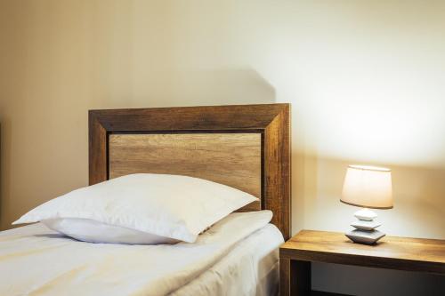 a bed with a wooden headboard next to a table at Memory House in Kutaisi
