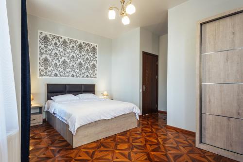 a bedroom with a white bed and a wooden floor at Memory House in Kutaisi