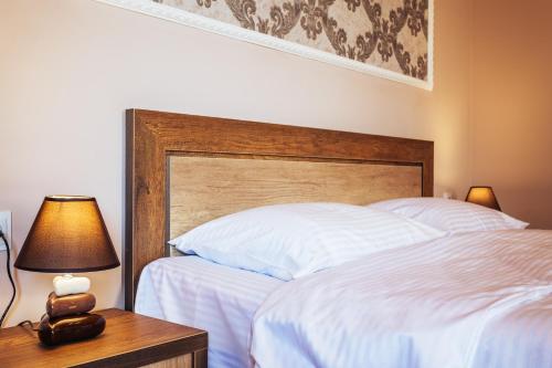 a bedroom with a white bed with a wooden headboard at Memory House in Kutaisi