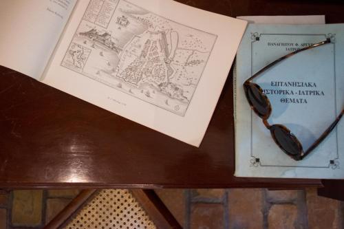 a table with a book and glasses on it at Corfu Town Mini Villa Private Pool Gardens in Mantoúkion