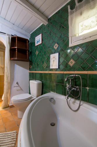 a green tiled bathroom with a tub and a toilet at Corfu Town Mini Villa Private Pool Gardens in Mantoúkion