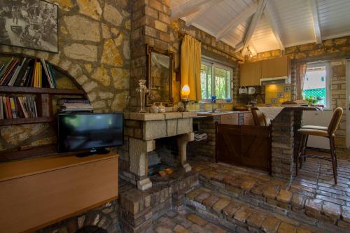 a living room with a stone fireplace and a tv at Corfu Town Mini Villa Private Pool Gardens in Mantoúkion