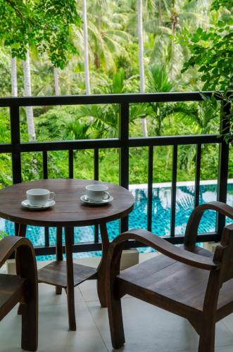 a wooden table and two chairs on a balcony with a view of a pool at Kirikayan Residences Koh Samui in Mae Nam