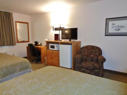 a hotel room with a bed and a tv and a chair at Homestead Inn and Suites in Hardin