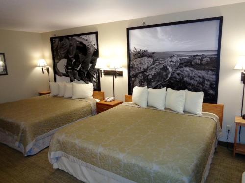 a hotel room with two beds and a painting on the wall at Homestead Inn and Suites in Hardin