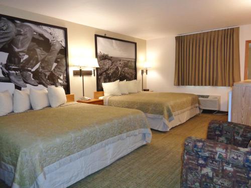 a hotel room with two beds and a chair at Homestead Inn and Suites in Hardin