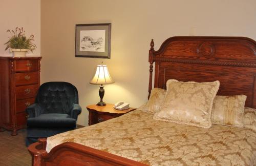 a bedroom with a bed and a chair and a lamp at Homestead Inn and Suites in Hardin