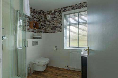 a bathroom with a toilet and a stone wall at Braeburn Guesthouse in Fort William
